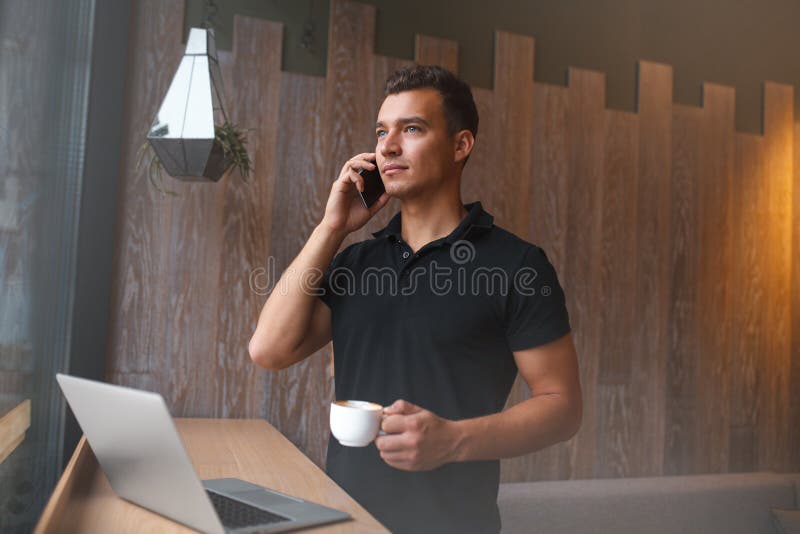 Lycklig ung man som använder bärbara datorn och mobiltelefonen på soffan royaltyfri foto Lycklig ung man som använder bärbara datorn och mobiltelefonen på soffan royaltyfri foto