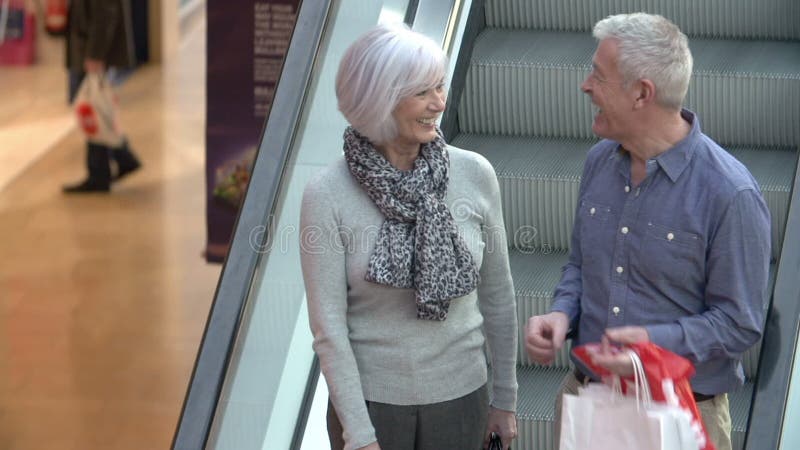 Lyckliga höga par på rulltrappan i shoppinggalleria lager videofilmer