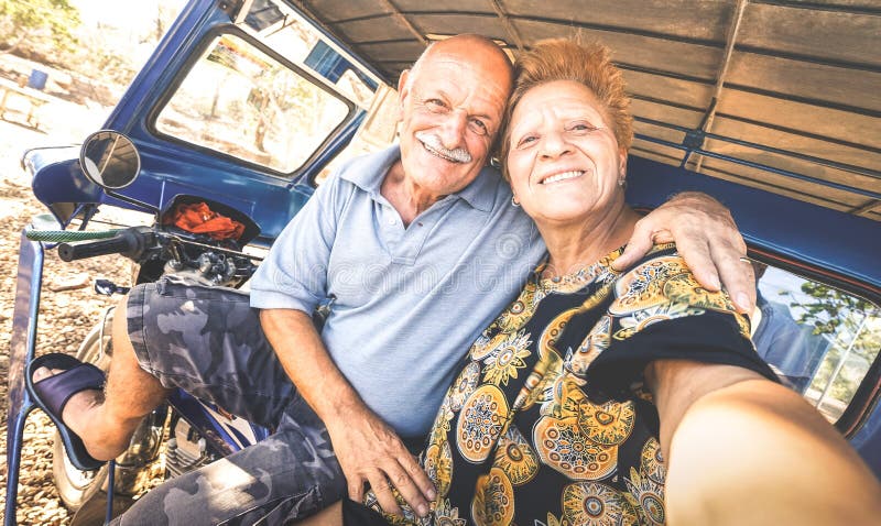 Lyckliga höga par som tar selfie på trehjulingen i Filippinerna, reser - begreppet av aktiv skämtsam åldring under avgång - royaltyfri fotografi Lyckliga höga par som tar selfie på trehjulingen i Filippinerna, reser - begreppet av aktiv skämtsam åldring under avgång - royaltyfri fotografi