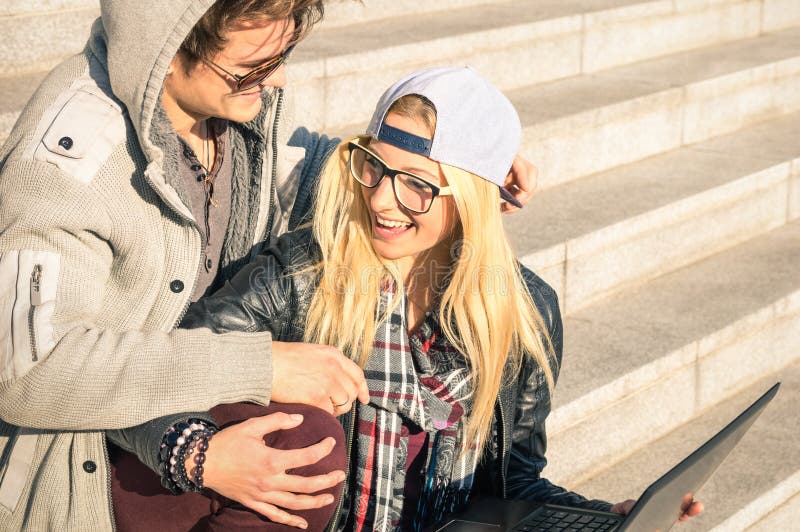 Lyckliga par för ung hipster med datorbärbara datorn i stadsområde royaltyfria foton Lyckliga par för ung hipster med datorbärbara datorn i stadsområde royaltyfria foton