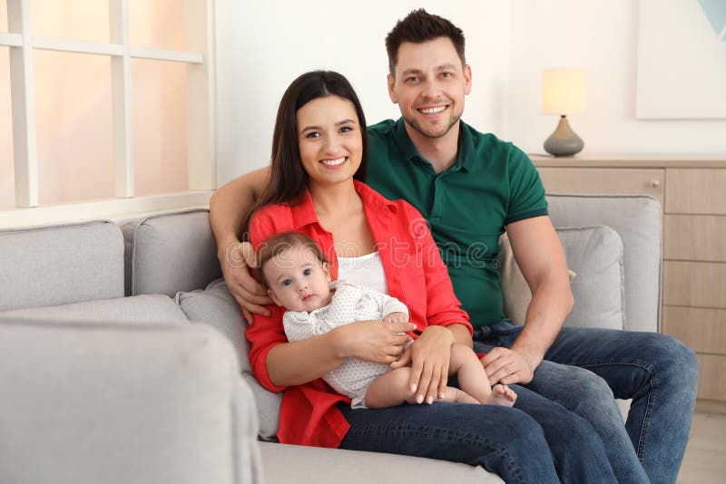 Lyckliga par med f?rtjusande behandla som ett barn p? soffan hemma royaltyfri bild Lyckliga par med f?rtjusande behandla som ett barn p? soffan hemma royaltyfri bild