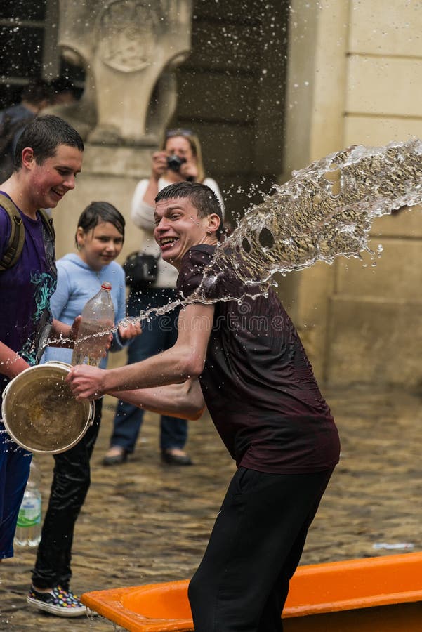 Lviv Ukraina - Maj 2, 2016: Hällande vatten för beröm på måndag efter påsk vid stadshuset Lyckliga pojkar som häller vatten på de