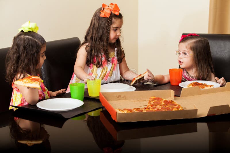Cute little cousins enjoying pizza together at home. Cute little cousins enjoying pizza together at home
