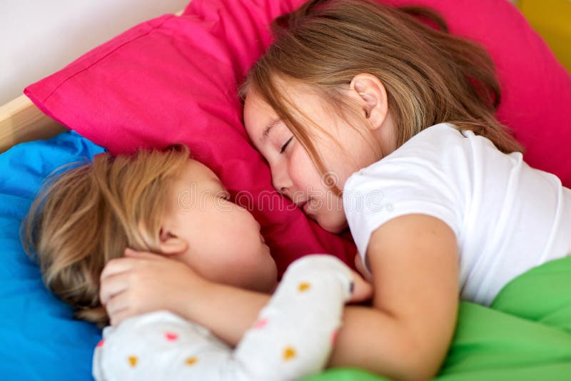 Lyckliga små flickor som hemma sover i säng fotografering för bildbyråer Lyckliga små flickor som hemma sover i säng fotografering för bildbyråer