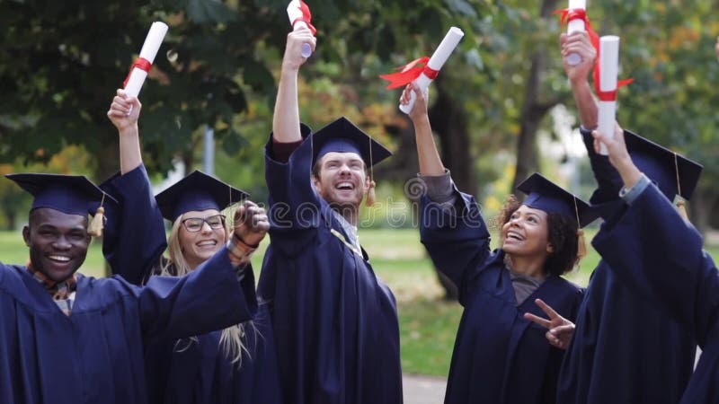 Lyckliga studenter i mortelbräden med diplom