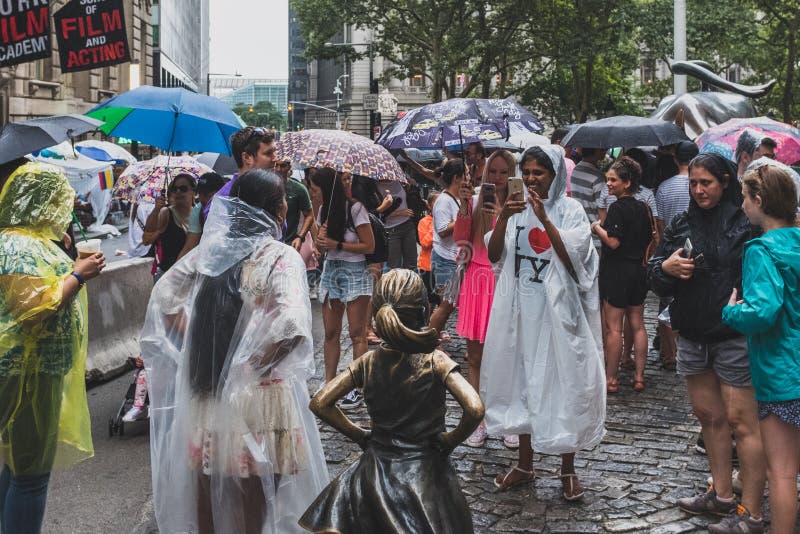 Lyckliga turister som tar foto med den oförskräckta flickastatyn i lägre Manhattan, i en regnig dag arkivfoton Lyckliga turister som tar foto med den oförskräckta flickastatyn i lägre Manhattan, i en regnig dag arkivfoton