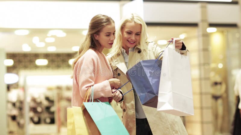 Lyckliga unga kvinnor med shoppingpåsar i galleria