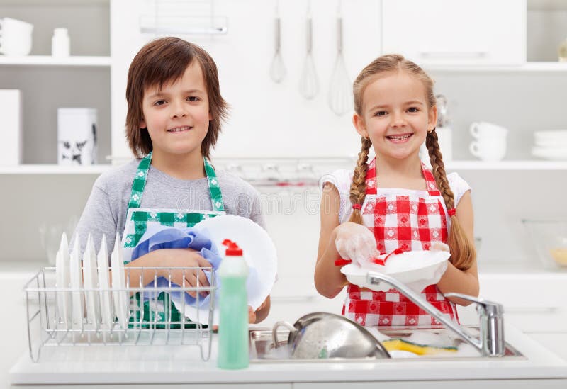 Happy kids helping in the kitchen doing the dishes. Happy kids helping in the kitchen doing the dishes
