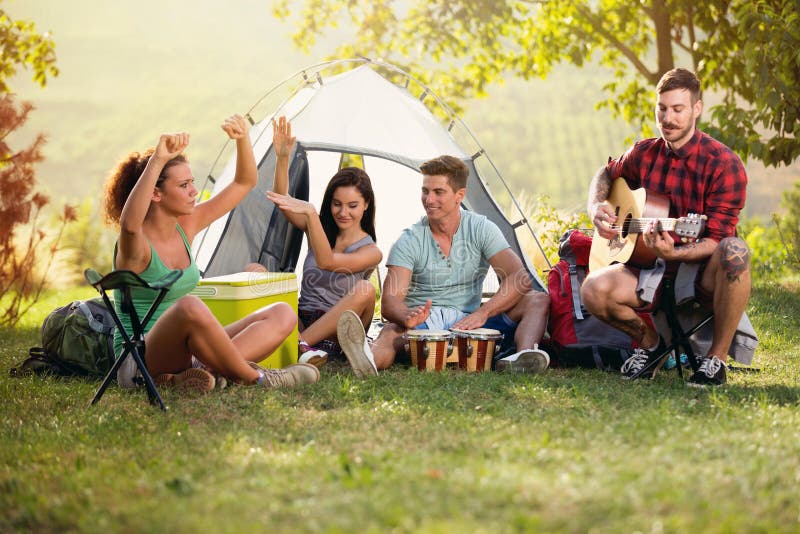 Lyckliga ungdomarsom har gyckel med musik på campa tur royaltyfri bild Lyckliga ungdomarsom har gyckel med musik på campa tur royaltyfri bild