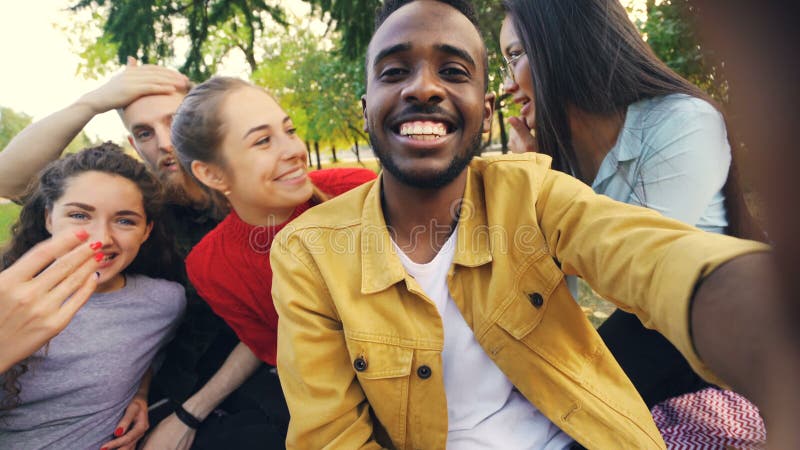 Lyckliga vänner gör den online-videopd appellen som ser kameran, talar och skrattar, medan afrikansk amerikanmannen rymmer