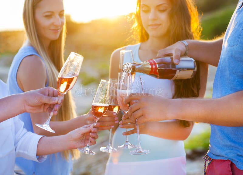 Lyckliga vänner som häller champagnemousserande vin in i exponeringsglasoutd royaltyfria bilder Lyckliga vänner som häller champagnemousserande vin in i exponeringsglasoutd royaltyfria bilder