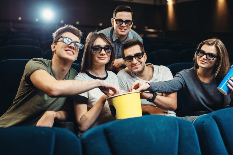Lyckliga vänner som håller ögonen på film i bio royaltyfri fotografi Lyckliga vänner som håller ögonen på film i bio royaltyfri fotografi