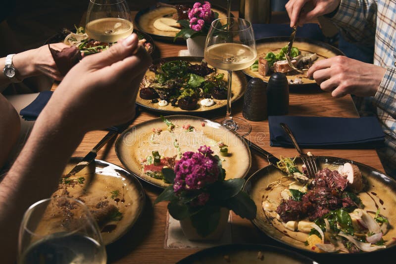 Lyckliga älska par som tycker om matställen och att sitta på tabell- och drinkvinet royaltyfri bild Lyckliga älska par som tycker om matställen och att sitta på tabell- och drinkvinet royaltyfri bild