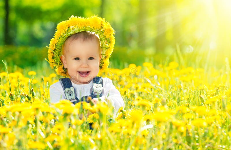 Lyckligt behandla som ett barn flickan i en krans på äng med gula blommor på t royaltyfri fotografi