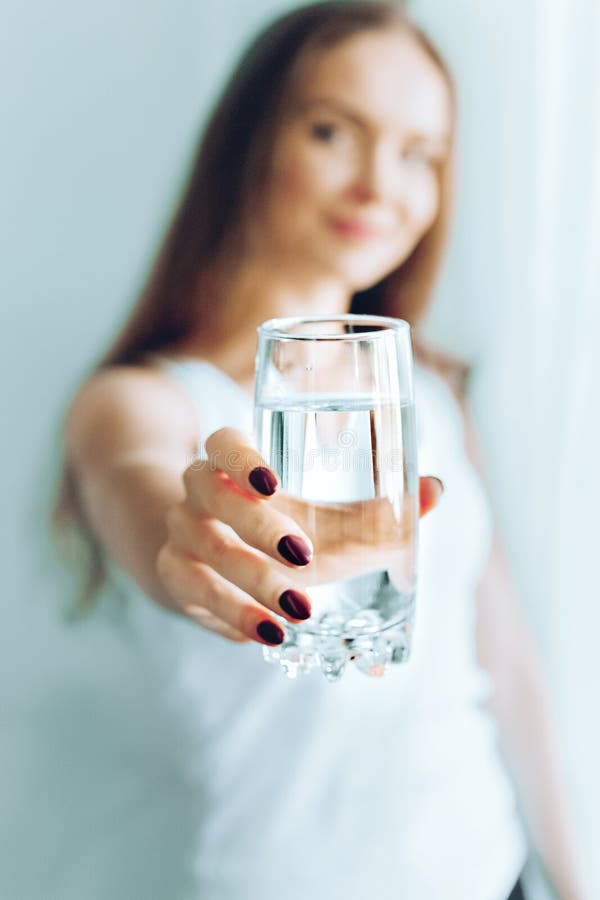 Lyckligt h?rligt dricksvatten f?r ung kvinna Le den caucasian kvinnliga modellen som rymmer genomskinligt exponeringsglas i henne royaltyfria bilder Lyckligt h?rligt dricksvatten f?r ung kvinna Le den caucasian kvinnliga modellen som rymmer genomskinligt exponeringsglas i henne royaltyfria bilder