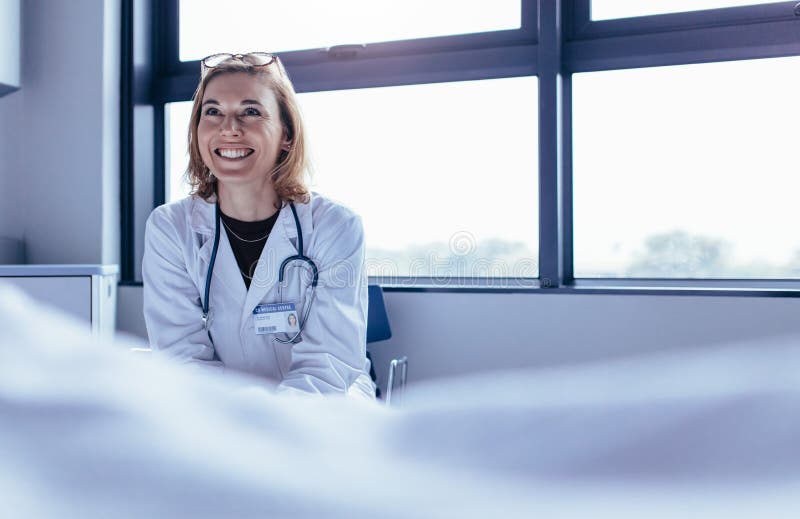 Lyckligt kvinnligt doktorssammanträde i sjukhusrum royaltyfri foto Lyckligt kvinnligt doktorssammanträde i sjukhusrum royaltyfri foto