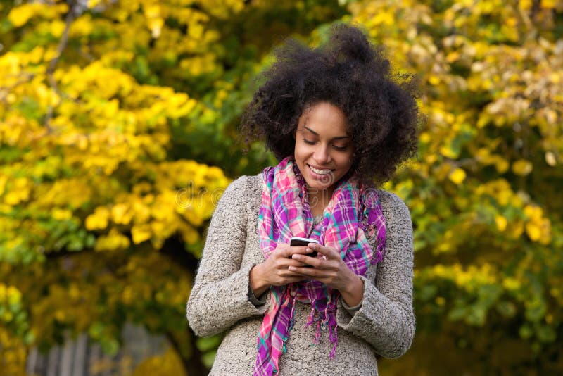 Lyckligt läs- textmeddelande för ung kvinna på mobiltelefonen