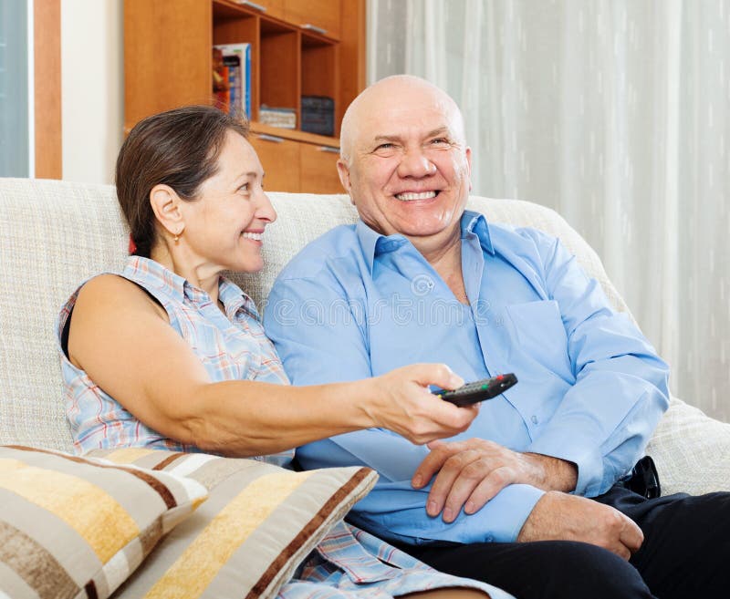Lyckligt mogna par som ser TV royaltyfri foto Lyckligt mogna par som ser TV royaltyfri foto