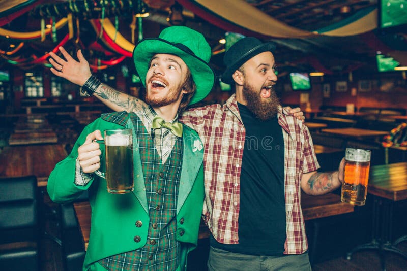 Lyckligt rymma för unga män rånar av öl och att sjunga tillsammans i bar De firar saitnpatricks dag Grabb på vänstra kläder royaltyfri fotografi Lyckligt rymma för unga män rånar av öl och att sjunga tillsammans i bar De firar saitnpatricks dag Grabb på vänstra kläder royaltyfri fotografi