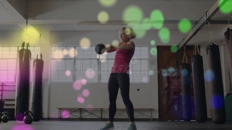 Lyftande kettlebellkvinna som motionerar över färgstarka bokeh-lampor animering lager videofilmer