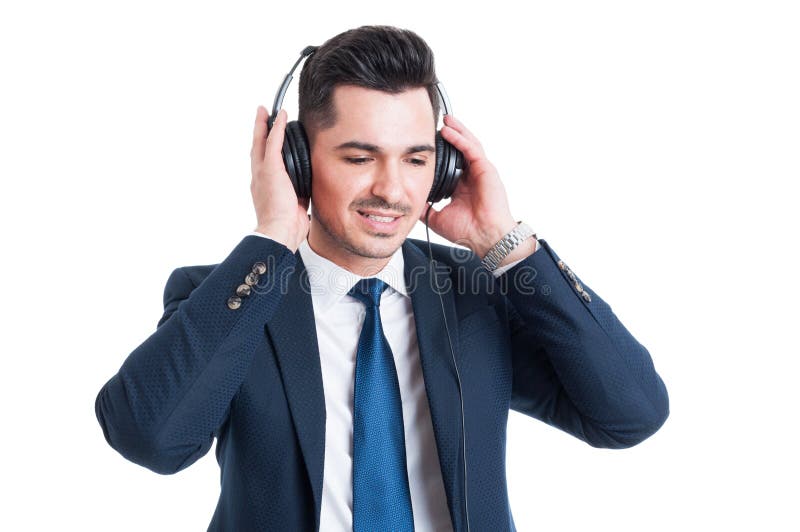 Lyssnande musik för ung affärsman på hörlurar som ser lycklig arkivbild Lyssnande musik för ung affärsman på hörlurar som ser lycklig arkivbild
