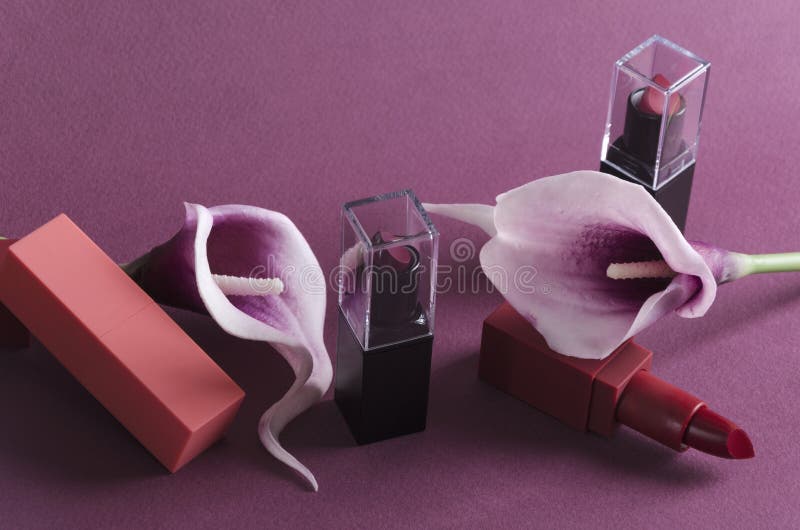 Lyxiga läppstift och purpurfärgade callas på den violetta bakgrunden arkivbilder Lyxiga läppstift och purpurfärgade callas på den violetta bakgrunden arkivbilder