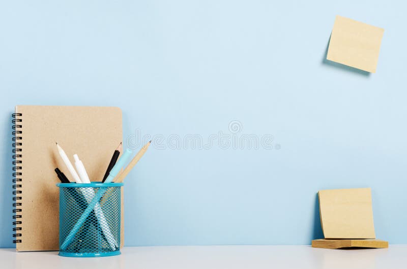 Lápis azuis, brancos e pretos, penas no suporte, caderno em uma tabela branca, etiquetas do ofício na parede do pombo, escritório imagem de stock Lápis azuis, brancos e pretos, penas no suporte, caderno em uma tabela branca, etiquetas do ofício na parede do pombo, escritório imagem de stock