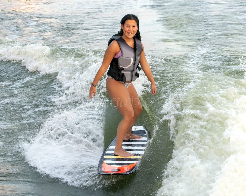 Lächeln amerasian Mädchenspur, die ein Motorboot auf spektakulären See in Oklahoma surft