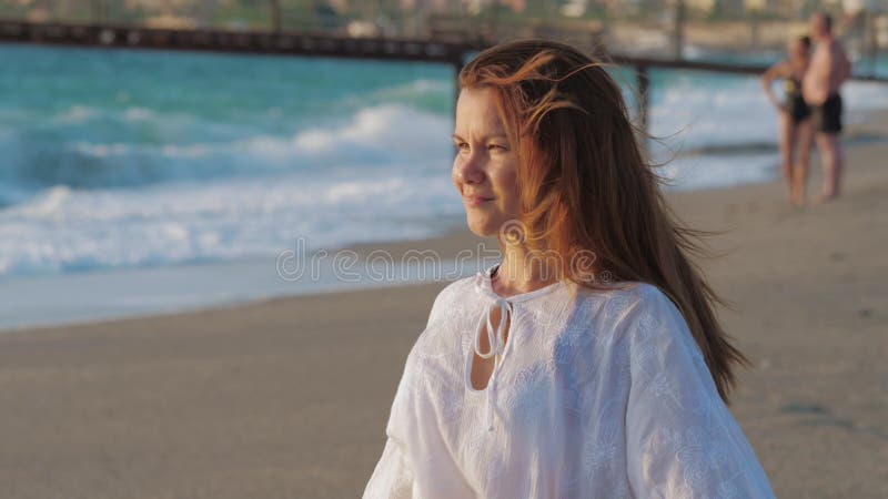 Lächeln einer jungen Frau entspannt und genießt das Leben auf einem sandigen Strand.