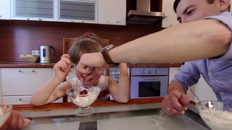 Lächeln Familie in der Küche zu Hause Eis zu essen. nettes kleines Mädchen, das Eis in einer Schüssel in der Küche essen