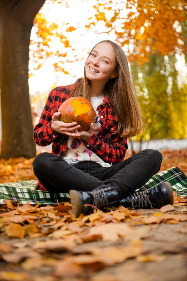 Lächeln jugendlich auf dem Plaid, das einen Kürbis hält lizenzfreies stockbild Lächeln jugendlich auf dem Plaid, das einen Kürbis hält lizenzfreies stockbild
