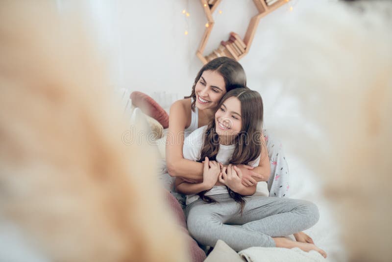 Lächeln Mutter, die ihre Tochter sitzt im Raum umarmt lizenzfreie stockfotos