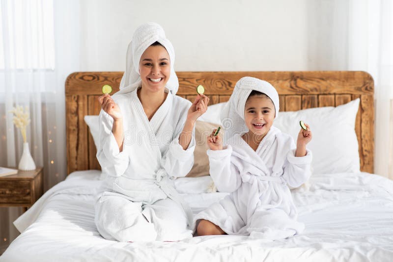 Lächelnd mutter und kleine mädchen zeigen gurke kreise stockfoto