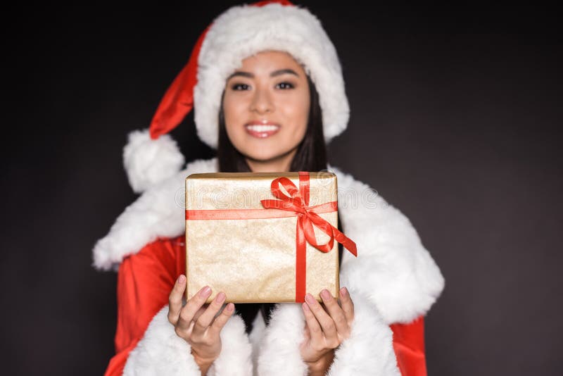 lächelnde asiatische Frau im schwarzen Badeanzug und in Sankt-Kostüm, ein Geschenk und ein Schauen zeigend stockfotografie lächelnde asiatische Frau im schwarzen Badeanzug und in Sankt-Kostüm, ein Geschenk und ein Schauen zeigend stockfotografie