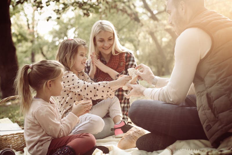 Lächelnde Familie, die Picknick zusammen im Park und in der Unterhaltung hat lizenzfreies stockbild Lächelnde Familie, die Picknick zusammen im Park und in der Unterhaltung hat lizenzfreies stockbild