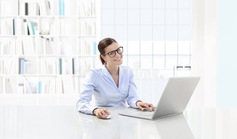 Lächelnde Frau des Geschäfts oder ein Sekretär, der an ihrem Schreibtischesprit arbeitet stockfoto