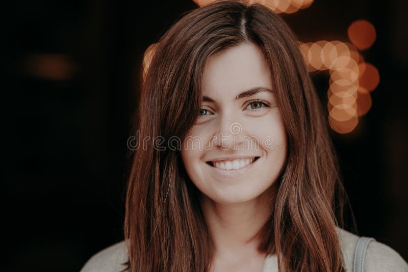 Lächelnde Frau des glücklichen Brunette mit dem dunklen Haar, weiße Zähne, Blicke positiv an der Kamera, zeigt ihr Naturschönheit stockbild Lächelnde Frau des glücklichen Brunette mit dem dunklen Haar, weiße Zähne, Blicke positiv an der Kamera, zeigt ihr Naturschönheit stockbild