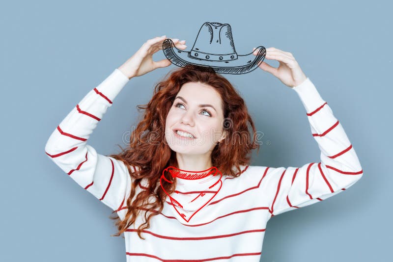 Lächelnde Frau, die einen Cowboyhut beim Sein an der Kostümpartei hält lizenzfreies stockbild Lächelnde Frau, die einen Cowboyhut beim Sein an der Kostümpartei hält lizenzfreies stockbild