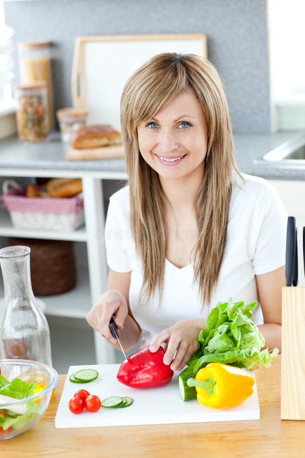 Lächelnde Frau, die einen Salat in der Küche zubereitet stockfotografie Lächelnde Frau, die einen Salat in der Küche zubereitet stockfotografie