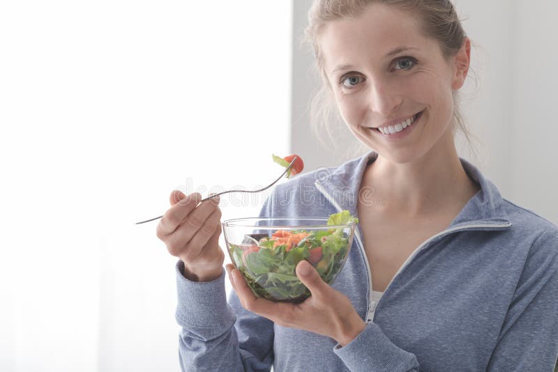 Lächelnde Frau, die einen Salat isst stockfotografie Lächelnde Frau, die einen Salat isst stockfotografie