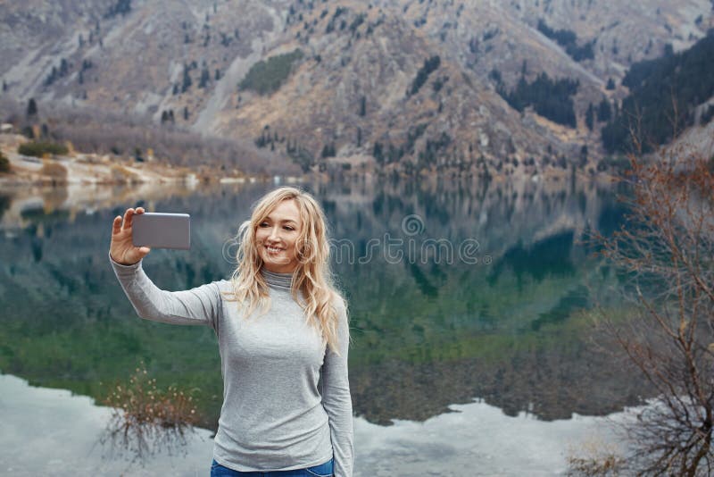 Lächelnde Frau macht selfie am See stockfotos