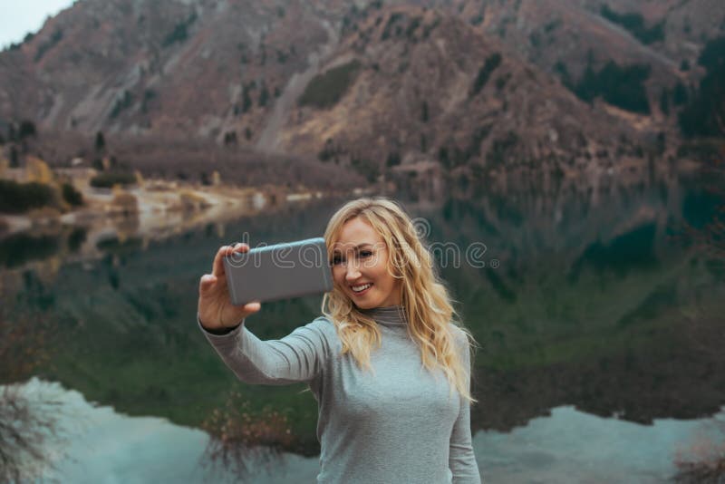 Lächelnde Frau macht selfie am See lizenzfreie stockfotografie