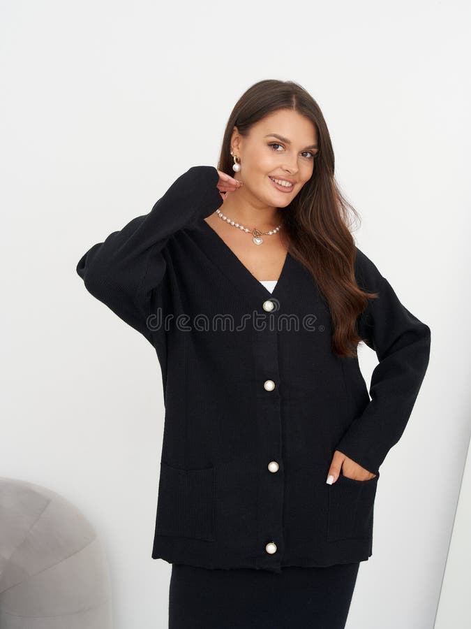 Lächelnde Frau mit langbraunem Haar, die einen schwarzen Buttonvordercardigan mit Perlknöpfen trägt, die mit Perle versehen sind lizenzfreie stockbilder