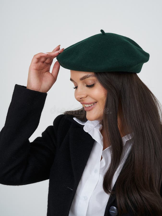 Lächelnde Frau passt grüne Beete an, während sie schwarzen Mantel über weißem Hemd trägt. Ihr langes braunes Haar kaskadiert über lizenzfreie stockfotos