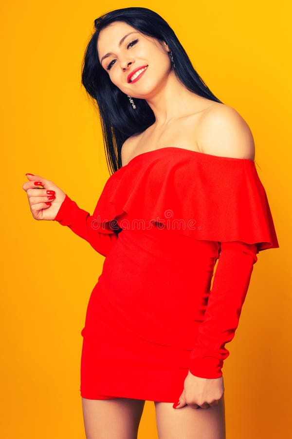 Lächelnde Frau in rotem Kleid mit fast gelbem Hintergrund stockfotografie Lächelnde Frau in rotem Kleid mit fast gelbem Hintergrund stockfotografie