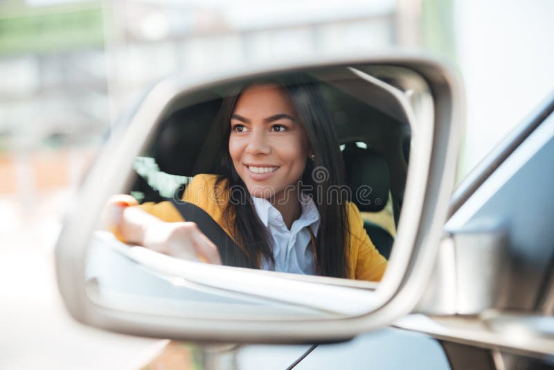 Lächelnde Geschäftsfrau im Seitenansichtautospiegel