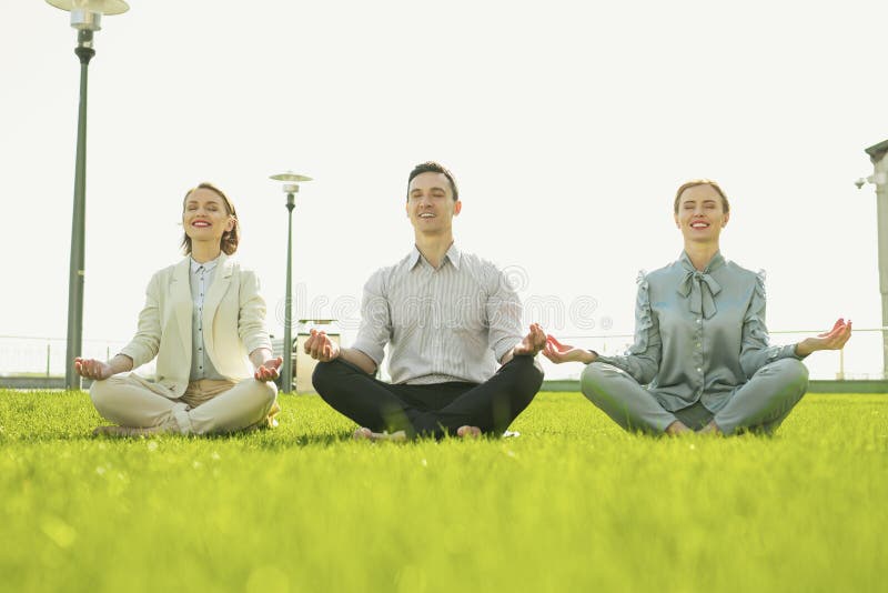 Lächelnde Geschäftskollegen, die Yoga auf Frischluft tun lizenzfreies stockfoto Lächelnde Geschäftskollegen, die Yoga auf Frischluft tun lizenzfreies stockfoto