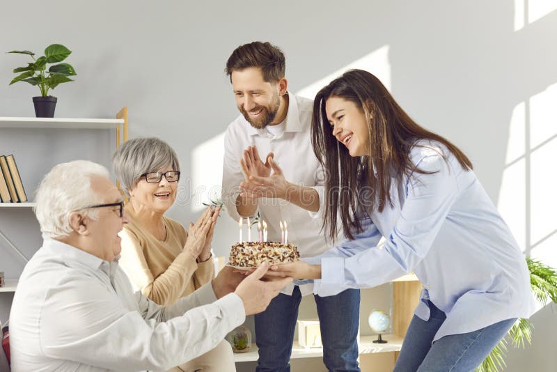 Lächelnde glückliche erwachsene Kinder gratulieren ihrem Seniorenvater geben ihm Kuchen zu Hause. stockfotografie