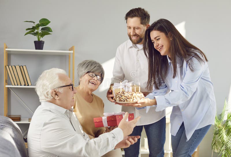 Lächelnde glückliche erwachsene Kinder gratulieren ihrem Seniorenvater geben ihm Kuchen zu Hause. lizenzfreie stockfotografie