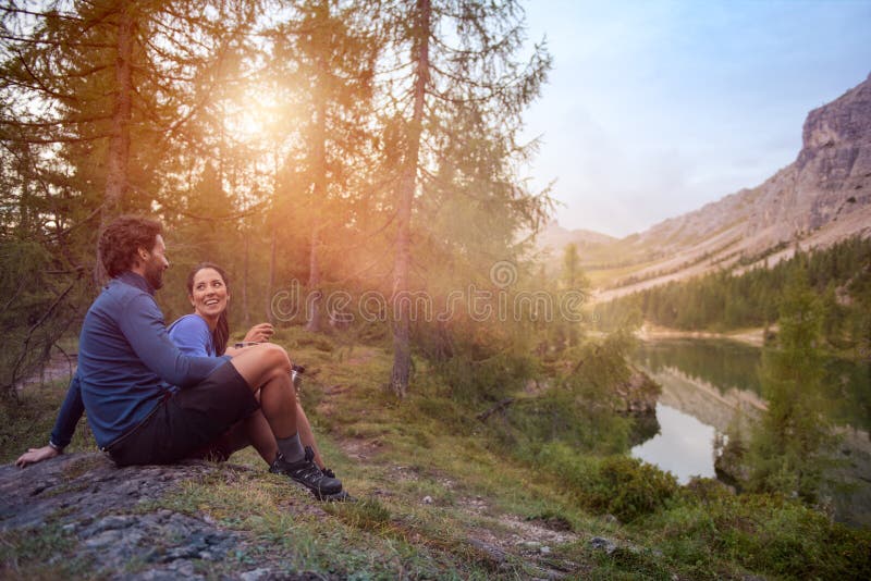 Lächelnde glückliche Mann- und Frauenpaare genießen Seepanoramaansicht mit Sonnenaufflackernlicht Gruppe Freundleutesommer stockfotos Lächelnde glückliche Mann- und Frauenpaare genießen Seepanoramaansicht mit Sonnenaufflackernlicht Gruppe Freundleutesommer stockfotos